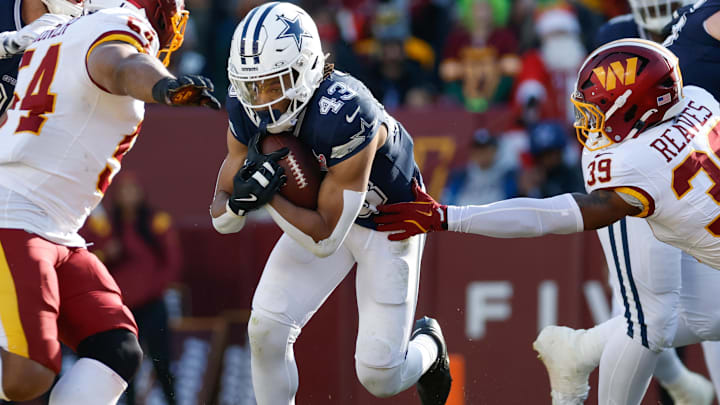 Dallas Cowboys running back Malik Davis carries the ball, defended by Washington Commanders safety Jeremy Reaves.