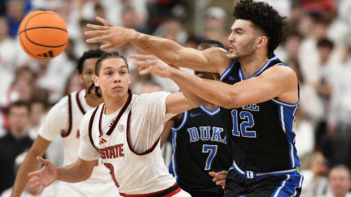 Mar 2, 2026; Raleigh, North Carolina, USA;  Duke Blue Devils forward Cameron Boozer (12) passes the ball around NC State Wolfpack guard Matt Able (3) during the first half at Lenovo Center. Mandatory Credit: Zachary Taft-Imagn Images