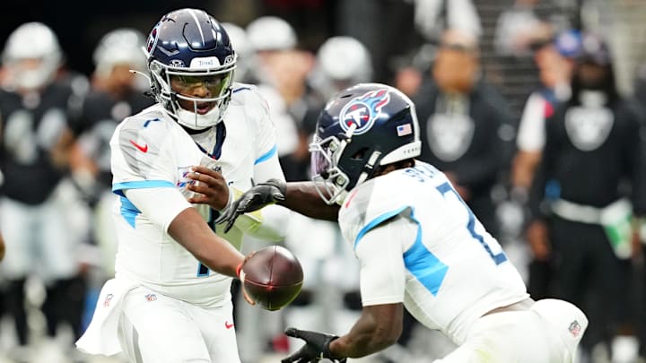 Tennessee Titans quarterback Cam Ward hands the ball off to running back Tyjae Spears.