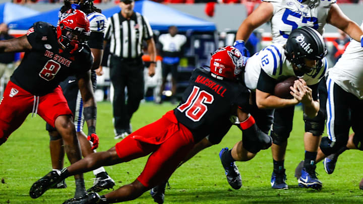 Nov 9, 2024; Raleigh, North Carolina, USA; North Carolina State Wolfpack cornerback Devon Marshall (16) tackles Duke Blue Devils quarterback Grayson Loftis (12) during the second half of the game at Carter-Finley Stadium. Mandatory Credit: Jaylynn Nash-Imagn Images Nov 9, 2024; Raleigh, North Carolina, USA; North Carolina State Wolfpack cornerback Devon Marshall (16) tackles Duke Blue Devils quarterback Grayson Loftis (12) during the second half of the game at Carter-Finley Stadium. Mandatory Credit: Jaylynn Nash-Imagn Images