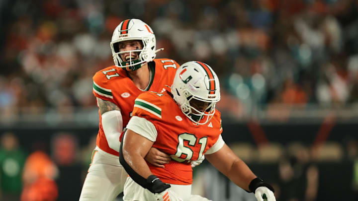 Sep 6, 2025; Miami Gardens, Florida, USA; Miami Hurricanes quarterback Carson Beck (11) helps offensive lineman Francis Mauigoa (61) against the Bethune-Cookman Wildcats during the second quarter at Hard Rock Stadium. Mandatory Credit: Sam Navarro-Imagn Images