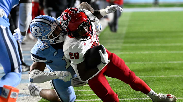 Nov 30, 2024; Chapel Hill, North Carolina, USA; North Carolina State Wolfpack running back Hollywood Smothers (20) is tackled near the goal line by North Carolina Tar Heels linebacker Amare Campbell (17) late in the fourth quarter at Kenan Memorial Stadium. Mandatory Credit: Bob Donnan-Imagn Images