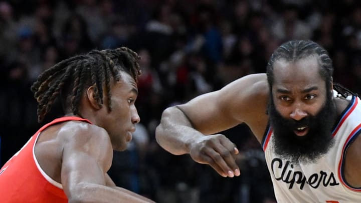 Los Angeles Clippers guard James Harden dribbles the ball past Toronto Raptors guard Ja'Kobe Walter.