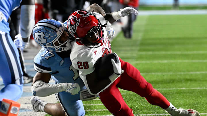 Nov 30, 2024; Chapel Hill, North Carolina, USA; North Carolina State Wolfpack running back Hollywood Smothers (20) is tackled near the goal line by North Carolina Tar Heels linebacker Amare Campbell (17) late in the fourth quarter at Kenan Memorial Stadium. Mandatory Credit: Bob Donnan-Imagn Images