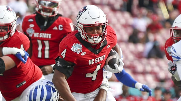 Dec 19, 2025; Tampa, FL, USA; NC State Wolfpack running back Jayden Scott (4)  is brought down by Memphis Tigers linebacker Sam Brumfield (3) in the first quarter during the Gasparilla Bowl at Raymond James Stadium. Mandatory Credit: Nathan Ray Seebeck-Imagn Images