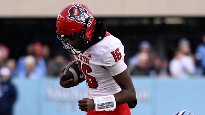 Nov 30, 2024; Chapel Hill, North Carolina, USA; North Carolina State Wolfpack quarterback CJ Bailey (16) is pushed out of bounds by North Carolina Tar Heels defensive back Alijah Huzzie (28) in the first quarter at Kenan Memorial Stadium. Mandatory Credit: Bob Donnan-Imagn Images