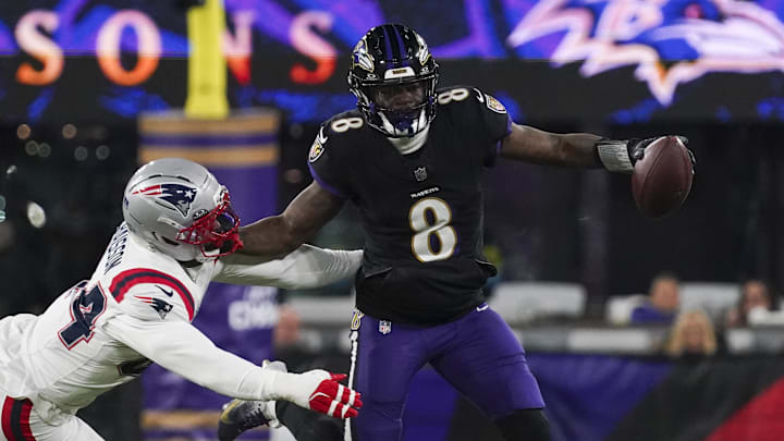 Dec 21, 2025; Baltimore, Maryland, USA; Baltimore Ravens quarterback Lamar Jackson (8) stiff arms New England Patriots linebacker K'Lavon Chaisson (44) during the first half of the game at M&T Bank Stadium. Mandatory Credit: James Lang-Imagn Images