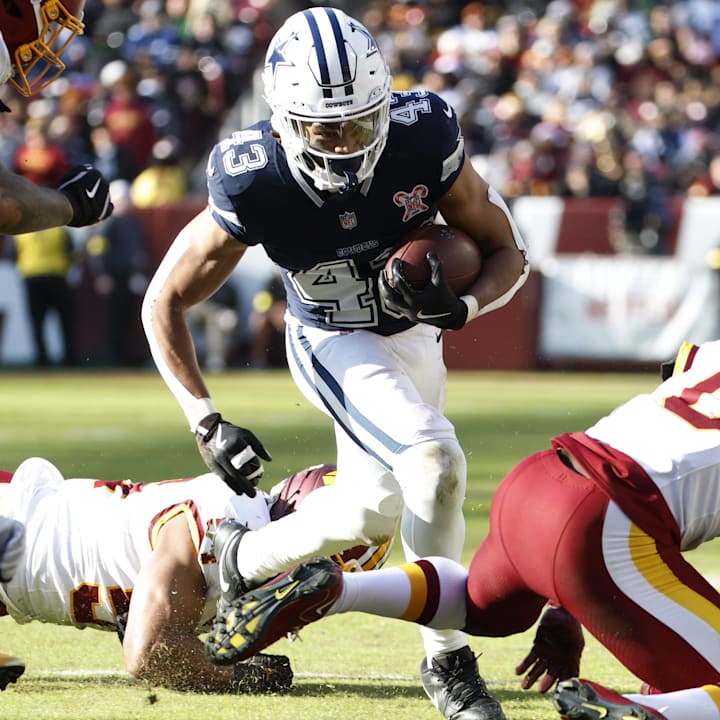 Dallas Cowboys running back Malik Davis carries the ball as Washington Commanders linebacker Frankie Luvu defends.