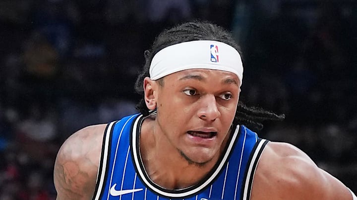 Orlando Magic forward Paolo Banchero controls the ball as Toronto Raptors forward Scottie Barnes tries to defend.