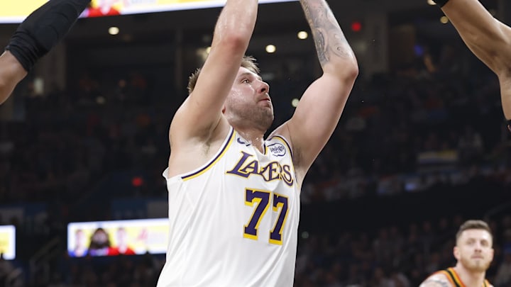 Apr 6, 2025; Oklahoma City, Oklahoma, USA; Los Angeles Lakers guard Luka Doncic (77) drives to the basket between Oklahoma City Thunder guard Shai Gilgeous-Alexander (2) and forward Jalen Williams (8) during the second quarter at Paycom Center. Mandatory Credit: Alonzo Adams-Imagn Images