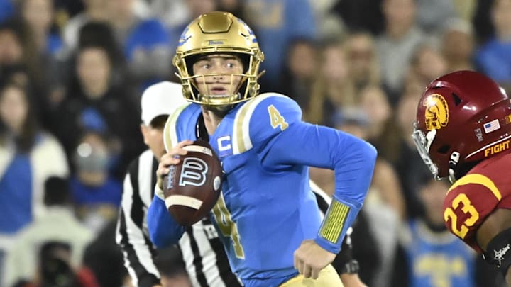 Nov 23, 2024; Pasadena, California, USA;  UCLA Bruins quarterback Ethan Garbers (4) scrambles out of the pocket chased by USC Trojans linebacker Desman Stephens II (23) during the first quarter at Rose Bowl. Mandatory Credit: Robert Hanashiro-Imagn Images