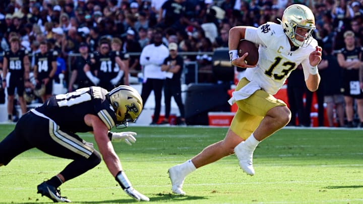 Sep 14, 2024; West Lafayette, Indiana, USA;  Notre Dame Fighting Irish quarterback Riley Leonard (13) runs past Purdue Boilermakers defensive back Dillon Thieneman (31) during the second quarter at Ross-Ade Stadium. Mandatory Credit: Marc Lebryk-Imagn Images
