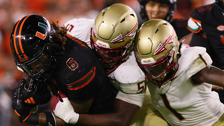 Oct 26, 2024; Miami Gardens, Florida, USA; Miami Hurricanes running back Damien Martinez (6) runs with the football against Florida State Seminoles defensive lineman KJ Sampson (56) and defensive back Shyheim Brown (1) during the fourth quarter at Hard Rock Stadium. Mandatory Credit: Sam Navarro-Imagn Images