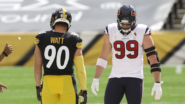 Sep 27, 2020; Pittsburgh, Pennsylvania, USA; NFL referee Shawn Smith (14) flips the coin as brothers Pittsburgh Steelers outside linebacker T.J. Watt (90) and Houston Texans defensive end J.J. Watt (99) take part before their game against at Heinz Field. The Steelers won 28-21