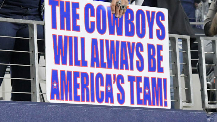 Dallas Cowboys fans hold up a sign referencing "America's Team." 