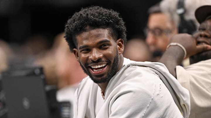 Jan 14, 2025; Dallas, Texas, USA; Colorado Buffaloes quarterback Shedeur Sanders laughs as he watches the game between the Dallas Mavericks and the Denver Nuggets during the second half at the American Airlines Center. Mandatory Credit: Jerome Miron-Imagn Images