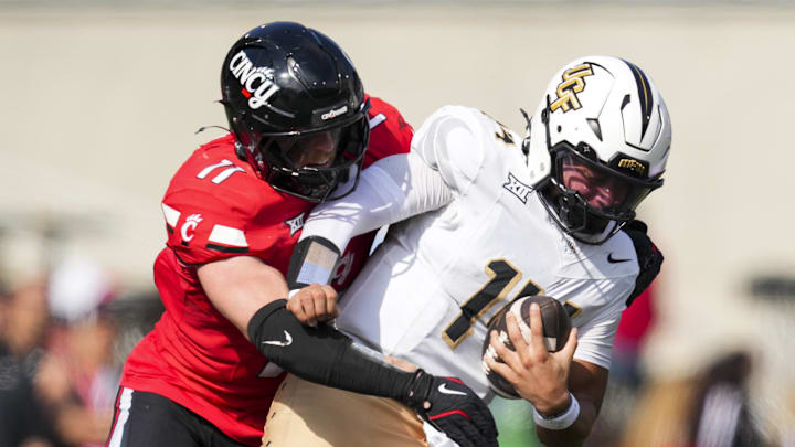Oct 11, 2025; Cincinnati, Ohio, USA; Cincinnati Bearcats linebacker Jake Golday (11) attempts to tackle UCF Knights quarterback Cam Fancher (14) in the second half at Nippert Stadium. Mandatory Credit: Aaron Doster-Imagn Images Oct 11, 2025; Cincinnati, Ohio, USA; Cincinnati Bearcats linebacker Jake Golday (11) attempts to tackle UCF Knights quarterback Cam Fancher (14) in the second half at Nippert Stadium. Mandatory Credit: Aaron Doster-Imagn Images