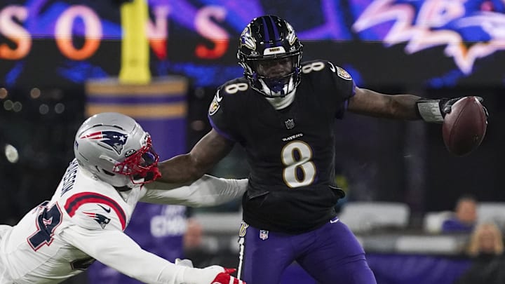 Dec 21, 2025; Baltimore, Maryland, USA;  Baltimore Ravens quarterback Lamar Jackson (8) stiff arms New England Patriots linebacker K'Lavon Chaisson (44) during the first half of the game at M&T Bank Stadium. Mandatory Credit: James Lang-Imagn Images
