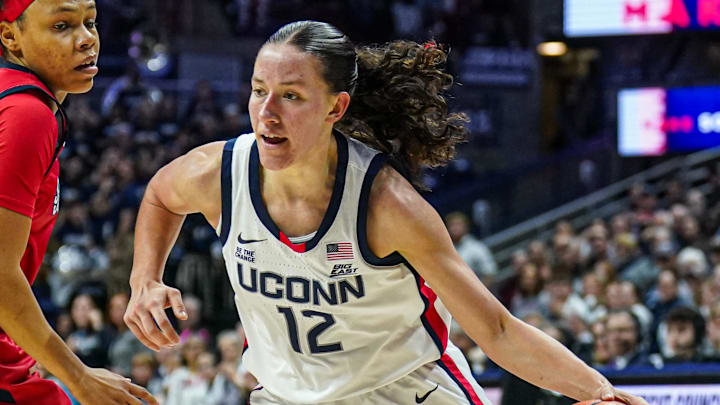 Feb 12, 2025; Storrs, Connecticut, USA; UConn Huskies guard Ashlynn Shade (12) drives the ball against St. John's Red Storm guard Ariana Vanderhoop (1) in the second half at Harry A. Gampel Pavilion. Mandatory Credit: David Butler II-Imagn Images