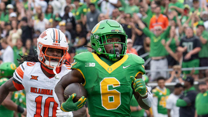 Oregon’s Noah Whittington, right, break for the end zone for the first touchdown of the game against Oklahoma State during the first quarter at Autzen.