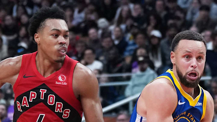 Golden State Warriors guard Stephen Curry controls the ball as Toronto Raptors forward Scottie Barnes tries to defend.