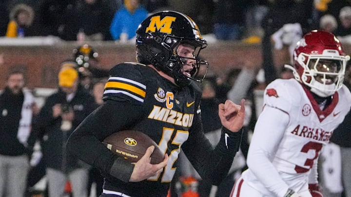 Missouri Tigers quarterback Brady Cook (12) runs in for the game-winning touchdown as Arkansas Razorbacks defensive back Doneiko Slaughter (3) looks on during the first half at Faurot Field at Memorial Stadium. 