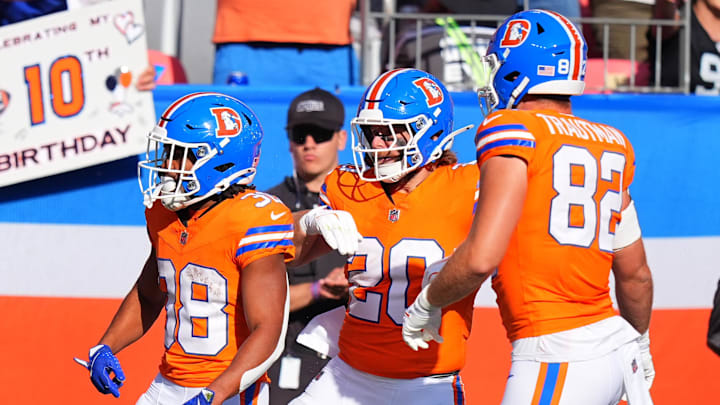 Oct 6, 2024; Denver, Colorado, USA; Denver Broncos running back Jaleel McLaughlin (38) celebrates his rushing touchdown with fullback Michael Burton (20) and tight end Adam Trautman (82) in the third quarter against the Las Vegas Raiders at Empower Field at Mile High. 