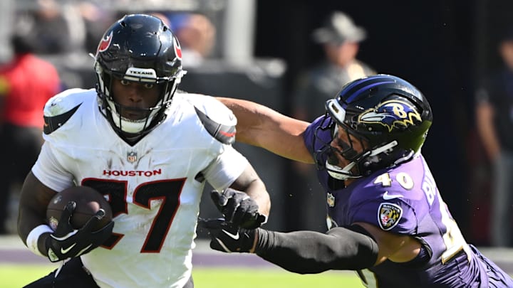 Oct 5, 2025; Baltimore, Maryland, USA; Houston Texans running back Woody Marks (27) runs for a gain past Baltimore Ravens linebacker Teddye Buchanan (40) during the second quarter at M&T Bank Stadium. Mandatory Credit: Rafael Suanes-Imagn Images