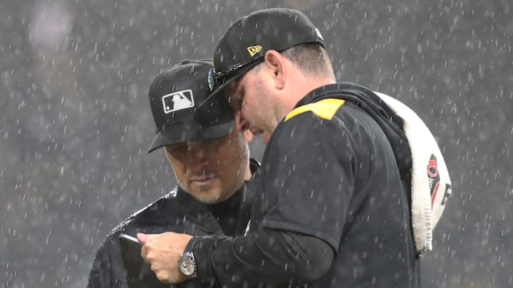 May 22, 2025; Pittsburgh, Pennsylvania, USA;  Pittsburgh Pirates grounds crew chief Mattt Brown (right) talks with MLB umpire crew chief Mark Wegner (14) as a heavy rain delays the game against the Milwaukee Brewers in the sixth inning at PNC Park. Mandatory Credit: Charles LeClaire-Imagn Images