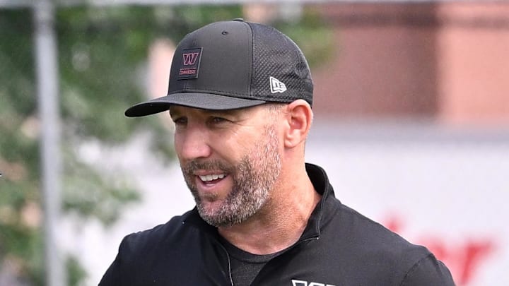 Washington Commanders owner Josh Harris and general manager Adam Peters speak to officials at training camp.