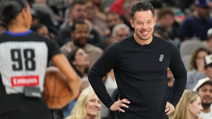 Apr 8, 2026; San Antonio, Texas, USA; San Antonio Spurs coach Mitch Johnson smiles during the first half against the Portland Trail Blazers at Frost Bank Center.