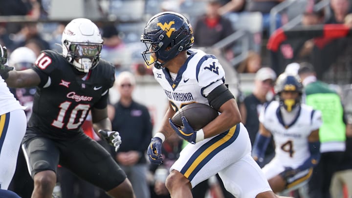 Nov 1, 2025; Houston, Texas, USA; West Virginia Mountaineers running back Diore Hubbard (20) rushes against Houston Cougars defensive end Latreveon McCutchin (10) in the first half at TDECU Stadium.