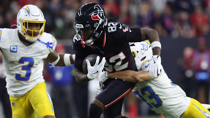 Jan 11, 2025; Houston, Texas, USA; Houston Texans wide receiver Diontae Johnson (82) runs the ball after a reception against Los Angeles Chargers defensive back Deane Leonard (33) and safety Derwin Jarnes Jr. (3) during the third quarter in an AFC wild card game at NRG Stadium. Mandatory Credit: Troy Taormina-Imagn Images