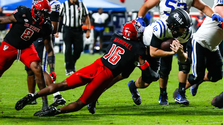 Nov 9, 2024; Raleigh, North Carolina, USA; North Carolina State Wolfpack cornerback Devon Marshall (16) tackles Duke Blue Devils quarterback Grayson Loftis (12) during the second half of the game at Carter-Finley Stadium. Mandatory Credit: Jaylynn Nash-Imagn Images