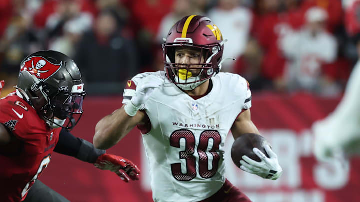 Jan 12, 2025; Tampa, Florida, USA; Washington Commanders running back Austin Ekeler (30) runs against Tampa Bay Buccaneers linebacker Yaya Diaby (0) during the fourth quarter of a NFC wild card playoff at Raymond James Stadium. Mandatory Credit: Kim Klement Neitzel-Imagn Images