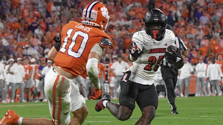Nov 2, 2024; Clemson, South Carolina, USA; Louisville Cardinals running back Isaac Brown (25) runs the ball against Clemson Tigers cornerback Jeadyn Lukus (10) during the second quarter at Memorial Stadium. Mandatory Credit: Ken Ruinard-Imagn Images