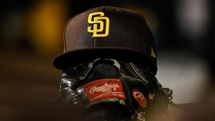 Jun 17, 2022; Denver, Colorado, USA; A detail view of a San Diego Padres hat on a glove in the dugout in the ninth inning against the Colorado Rockies at Coors Field. Mandatory Credit: Isaiah J. Downing-Imagn Images