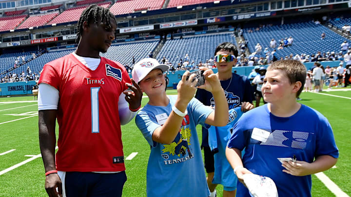 Tennessee Titans quarterback Cam Ward takes a selfie as he walks with kids on the field.