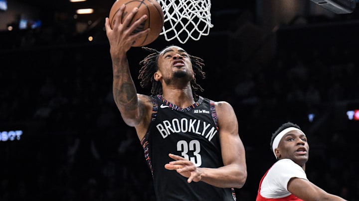 Dec 21, 2025; Brooklyn, New York, USA; Brooklyn Nets center Nic Claxton (33) drives to the basket while defended by Toronto Raptors guard Ja'Kobe Walter (14) during the first half at Barclays Center. Mandatory Credit: John Jones-Imagn Images