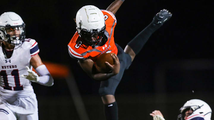 Lely Trojans running back Jayvian Tanelus (0) hurdles an Estero Wildcats defender during the fourth quarter of a spring football game at Lely High School in Naples on Friday, May 19, 2023.