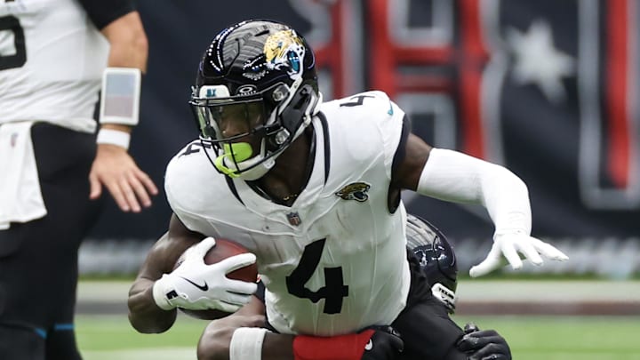 Sep 29, 2024; Houston, Texas, USA;  Jacksonville Jaguars running back Tank Bigsby (4) is tackled by Houston Texans linebacker Azeez Al-Shaair (0) in the second half at NRG Stadium. Mandatory Credit: Thomas Shea-Imagn Images