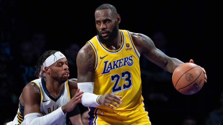 Lakers forward LeBron James dribbles the basketball against Indiana Pacers guard Buddy Hield during a game in December 2023.