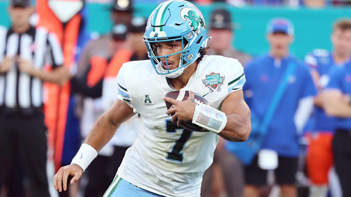 Dec 20, 2024; Tampa, FL, USA; Tulane Green Wave quarterback Ty Thompson (7) runs with the ball as Florida Gators defensive back Jordan Castell (14) tackles during the second quarter at Raymond James Stadium
