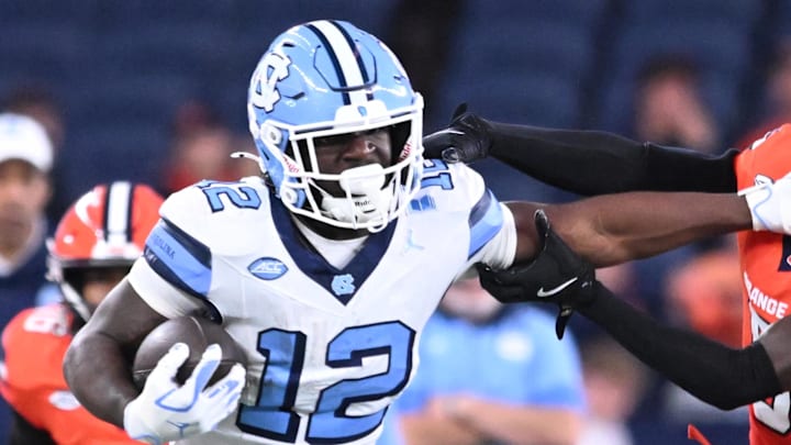 Oct 31, 2025; Syracuse, New York, USA; North Carolina Tar Heels running back Demon June (12) gives a stiff arm to Syracuse Orange defensive back Braheem Long Jr. (0) while scoring a touchdown in the third quarter at the JMA Wireless Dome. Mandatory Credit: Mark Konezny-Imagn Images