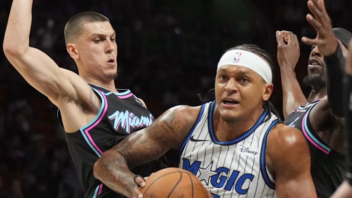 Mar 14, 2026; Miami, Florida, USA; Orlando Magic forward Paolo Banchero (5) splits the defense of Miami Heat guard Tyler Herro (14) and Miami Heat center Bam Adebayo (13) during the first half at Kaseya Center. Mandatory Credit: Jim Rassol-Imagn Images Mar 14, 2026; Miami, Florida, USA; Orlando Magic forward Paolo Banchero (5) splits the defense of Miami Heat guard Tyler Herro (14) and Miami Heat center Bam Adebayo (13) during the first half at Kaseya Center. Mandatory Credit: Jim Rassol-Imagn Images