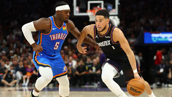 Apr 27, 2026; Phoenix, Arizona, USA; Oklahoma City Thunder guard Luguentz Dort (5) defends against Phoenix Suns guard Devin Booker (1) in the second half during game four of the first round of the 2026 NBA Playoffs at Mortgage Matchup Center. Mandatory Credit: Mark J. Rebilas-Imagn Images