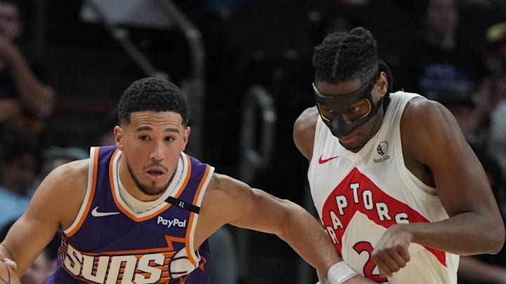 Phoenix Suns guard Devin Booker drives past Toronto Raptors forward Jonathan Mogbo.