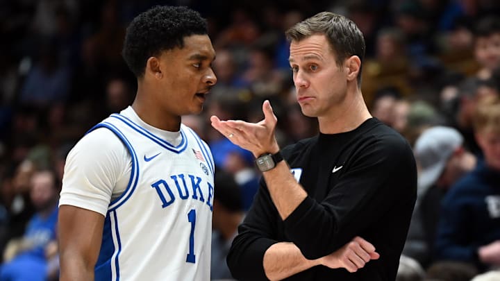 Jan 26, 2026; Durham, North Carolina, USA; Duke Blue Devils head coach Jon Scheyer (right) talks to guard Caleb Foster (1) during the second half against the Louisville Cardinals at Cameron Indoor Stadium. Mandatory Credit: Rob Kinnan-Imagn Images