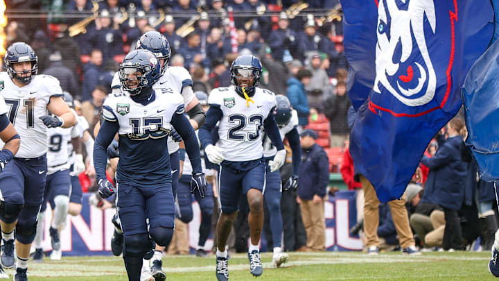 UConn's Rante Jones, left, and Tui Faumuina-Brown lead the team out of the tunnel during the third annual Wasabi Fenway Bowl against North Carolina at Fenway Park on Saturday, Dec. 28, 2024.