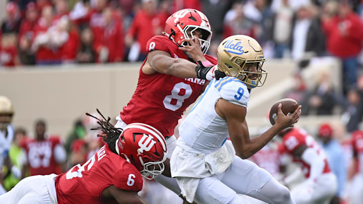 Oct 25, 2025; Bloomington, Indiana, USA; UCLA Bruins quarterback Nico Iamaleava (9) runs with the ball against Indiana Hoosiers defensive linemen Mikail Kamara (6) and Stephen Daley (8) during the second half at Memorial Stadium. Mandatory Credit: Robert Goddin-Imagn Images